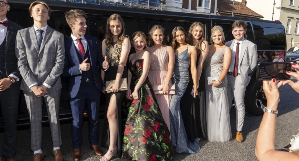 Un gruppo di persone ben vestite si trova davanti a un edificio nel campus della Taunton School.