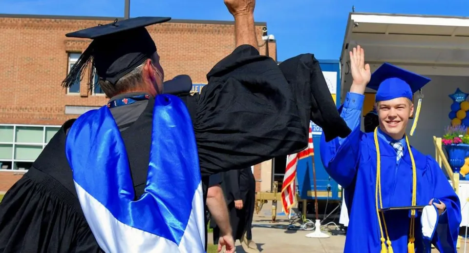 I diplomati della Ottawa Technical Secondary School festeggiano il diploma davanti a un edificio in mattoni.