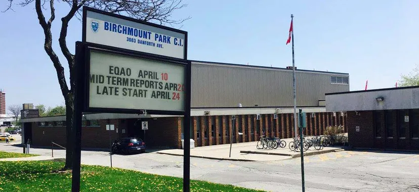 Il cartello del Birchmount Park Collegiate Institute informa sulle pagelle intermedie e sugli orari di inizio ritardato delle lezioni davanti all'edificio scolastico con biciclette.