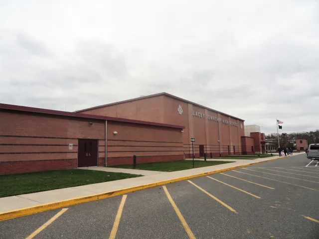 Das große Backsteingebäude mit rotem Dach von Lacey Township High School ist von einem Parkplatz und Grünflächen umgeben.