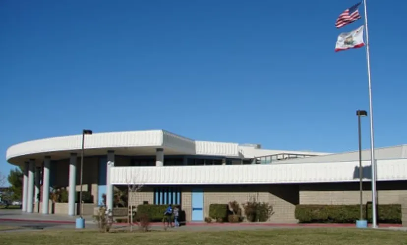 L'edificio moderno e bianco della Littlerock High School con un tetto curvo e una bandiera americana davanti.
