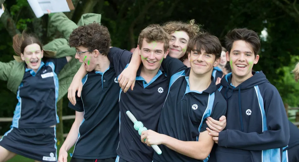Un gruppo di studenti della Bedales School è insieme davanti a uno sfondo verde di alberi e fogliame.