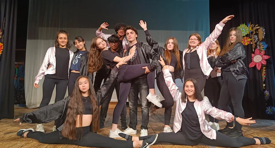 Un gruppo di studenti della St. Bees School posa insieme su un palco con uno sfondo scuro.