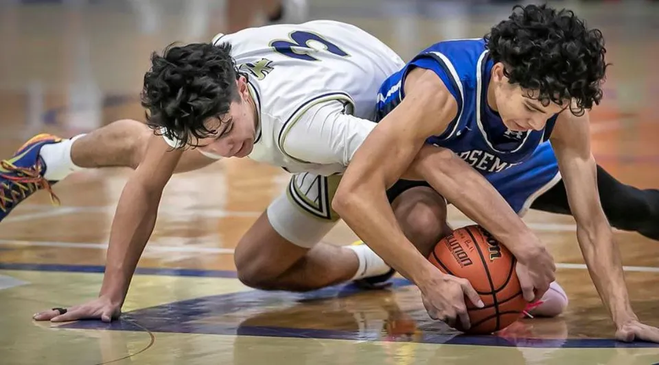 Due giocatori di basket lottano intensamente per il pallone sul campo della St. Michael's Regional High.
