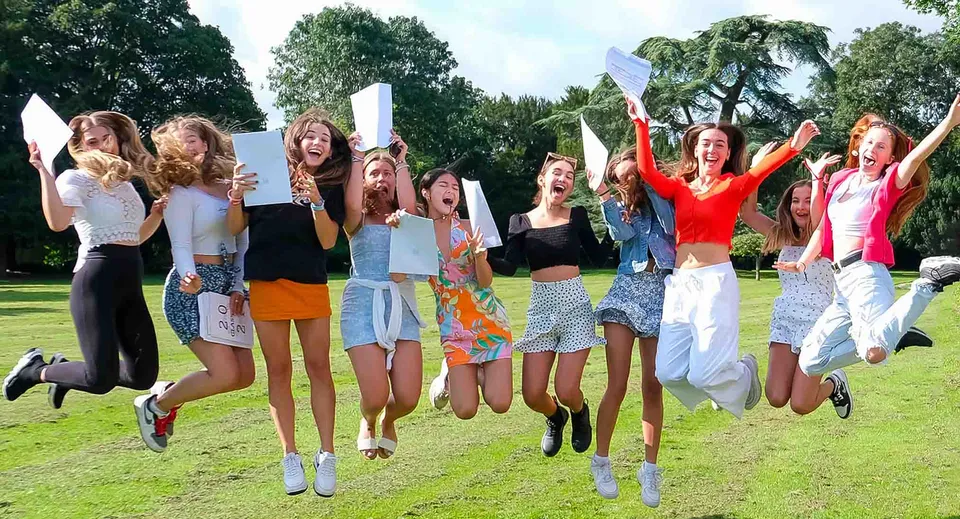Un gruppo di giovani studentesse del Thornton College festeggia insieme e salta su un prato all'aperto.