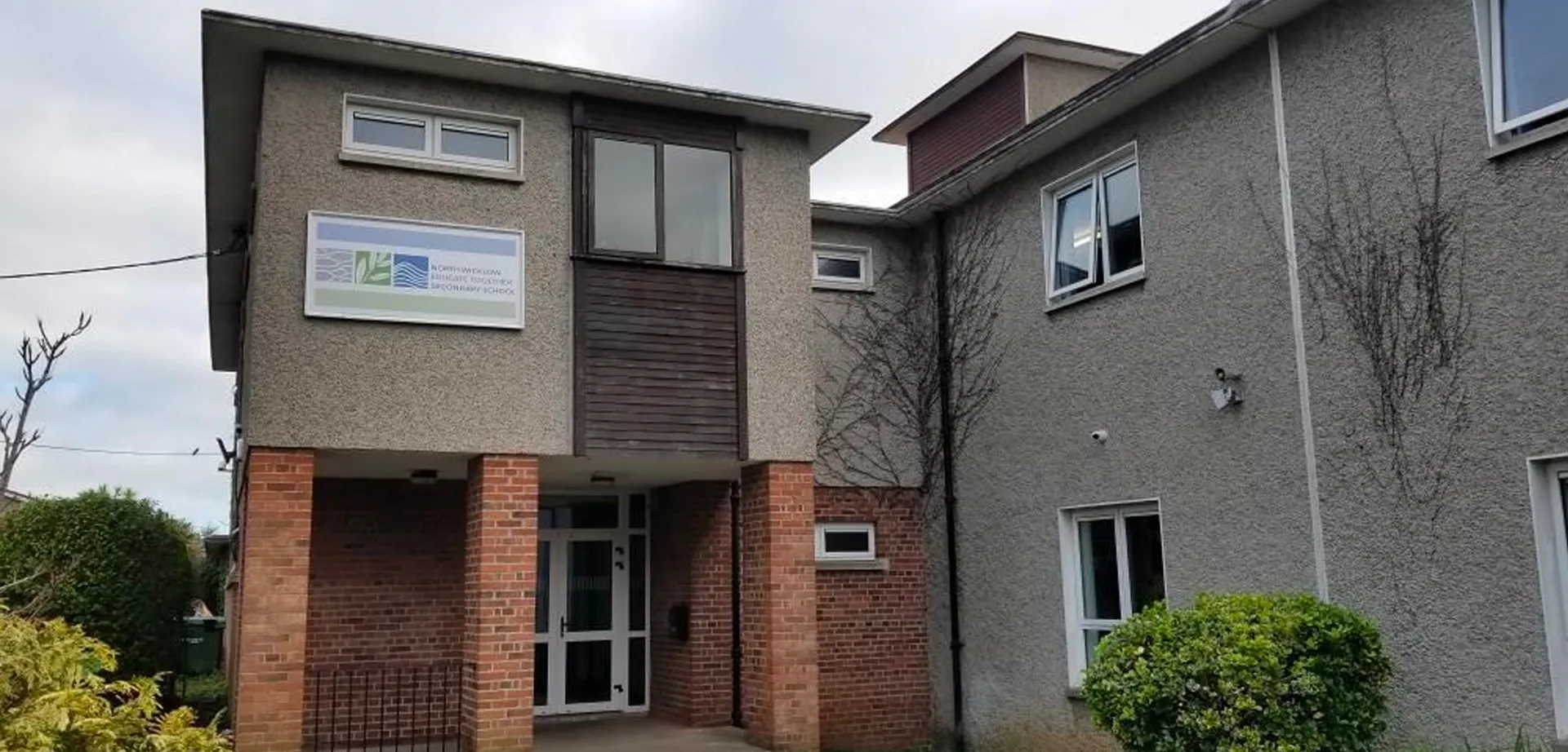 L'edificio residenziale a più piani con facciata mista in mattoni e intonaco si trova davanti alla North Wicklow Educate Together Secondary School.