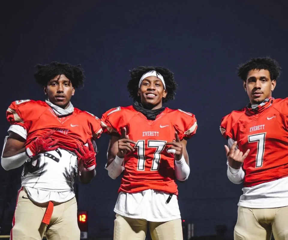 Tre studenti della Mount Everett Regional High School indossano maglie da football rosse con i numeri 17 e 7 su uno sfondo scuro.