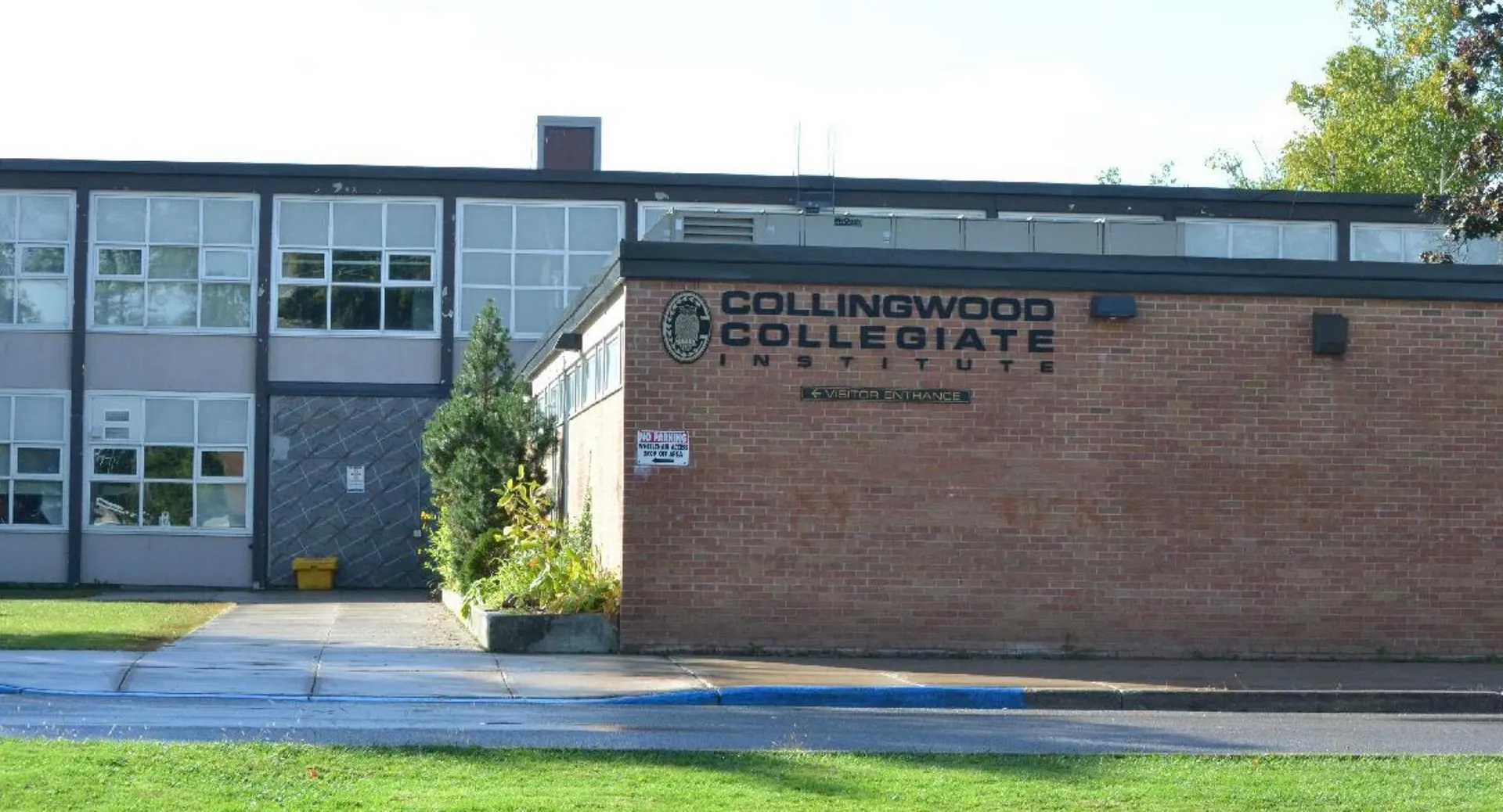 L'edificio del Collingwood Collegiate Institute è circondato da alberi e da un prato verde.