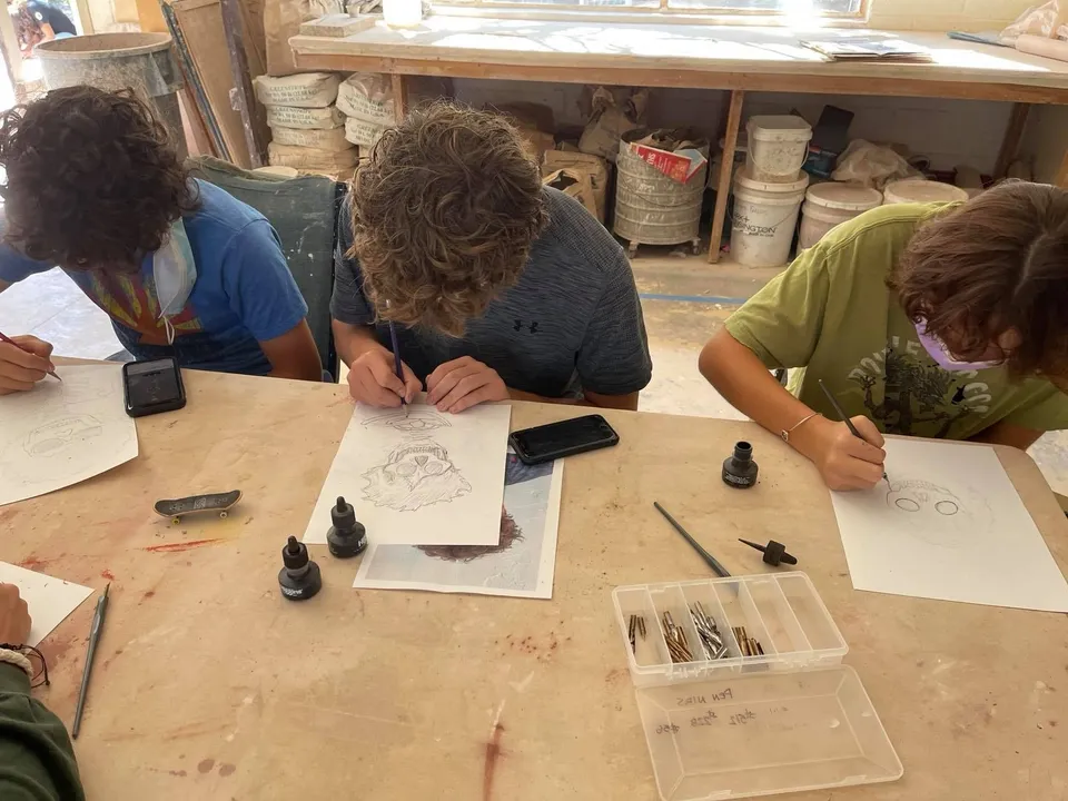 Studenti della Verde Valley School siedono insieme a un tavolo e lavorano a un'attività di disegno creativo.