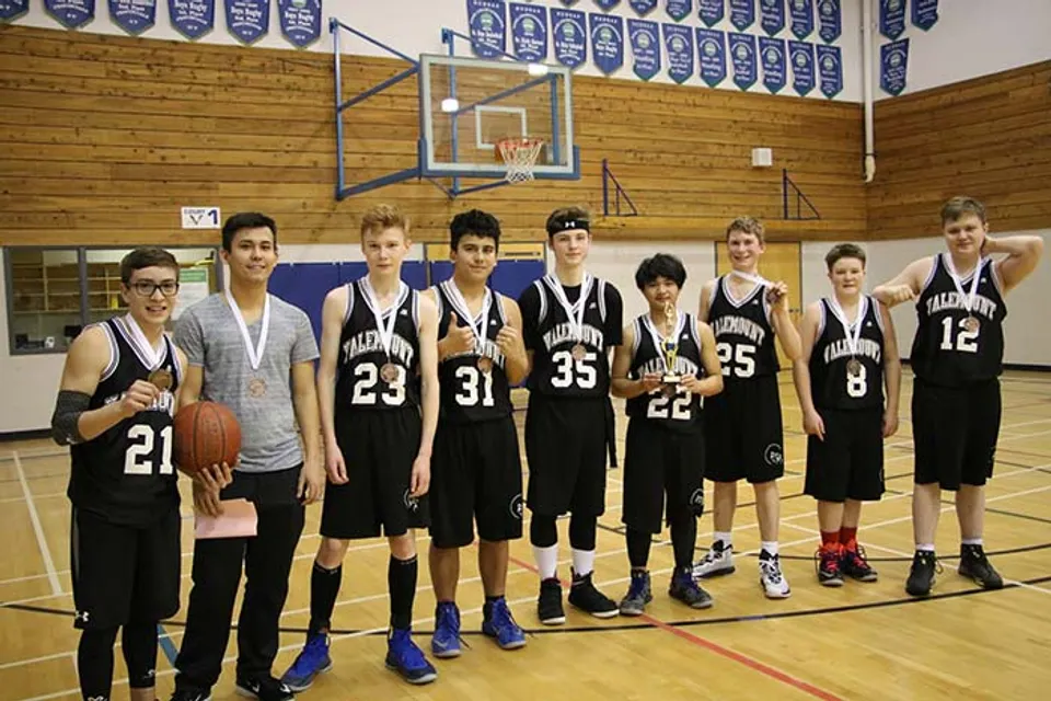 Un gruppo di studenti della Valemount Secondary School si trova in palestra davanti a un canestro da basket.