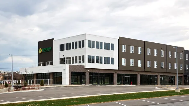 Il moderno edificio della Martin Luther High School con facciata in vetro e mattoni si trova su un parcheggio pavimentato sotto un cielo nuvoloso.