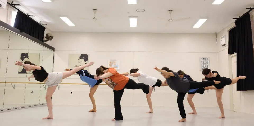 Studentesse della Jannali High School praticano una posizione di danza in uno studio con specchi.