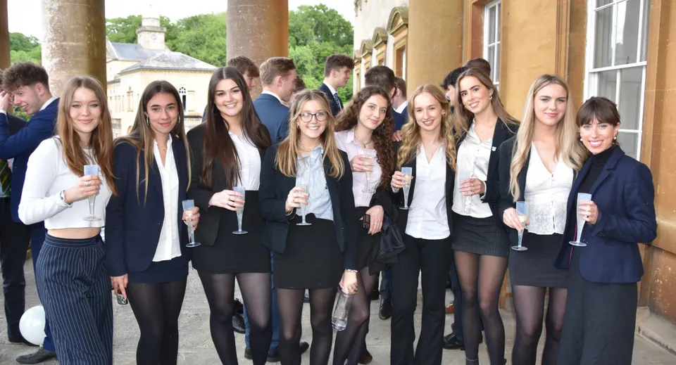 Un gruppo di giovani donne in abito formale si trova davanti a un edificio storico nel campus del Prior Park College.