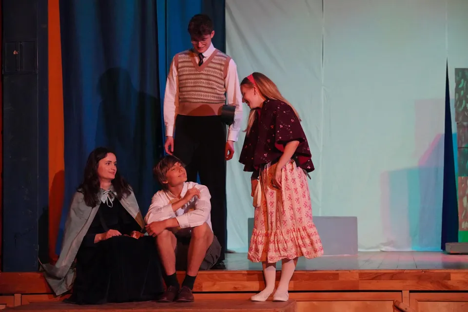 Studenti della Edinburgh Steiner School si esibiscono in uno spettacolo teatrale su un palco, indossando costumi colorati.
