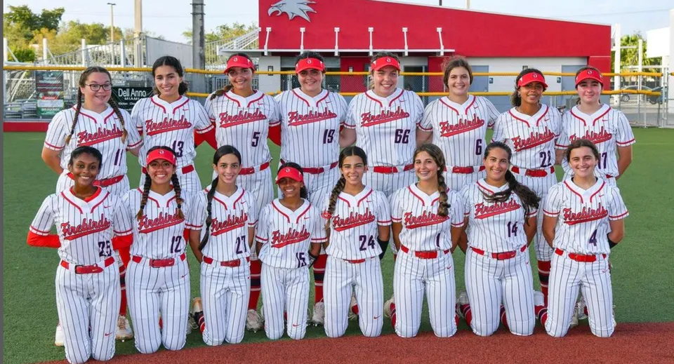 Un gruppo di giocatori di baseball con uniformi bianche e rosse si trova sul campo di gioco della Miami-Dade County Public School.