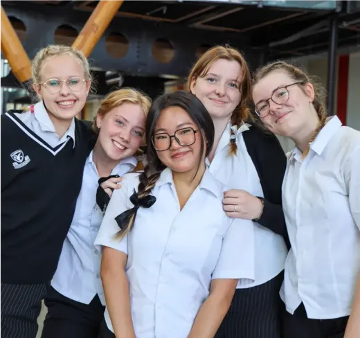 Fünf Schülerinnen in Schuluniform lächeln gemeinsam in Neuseeland
