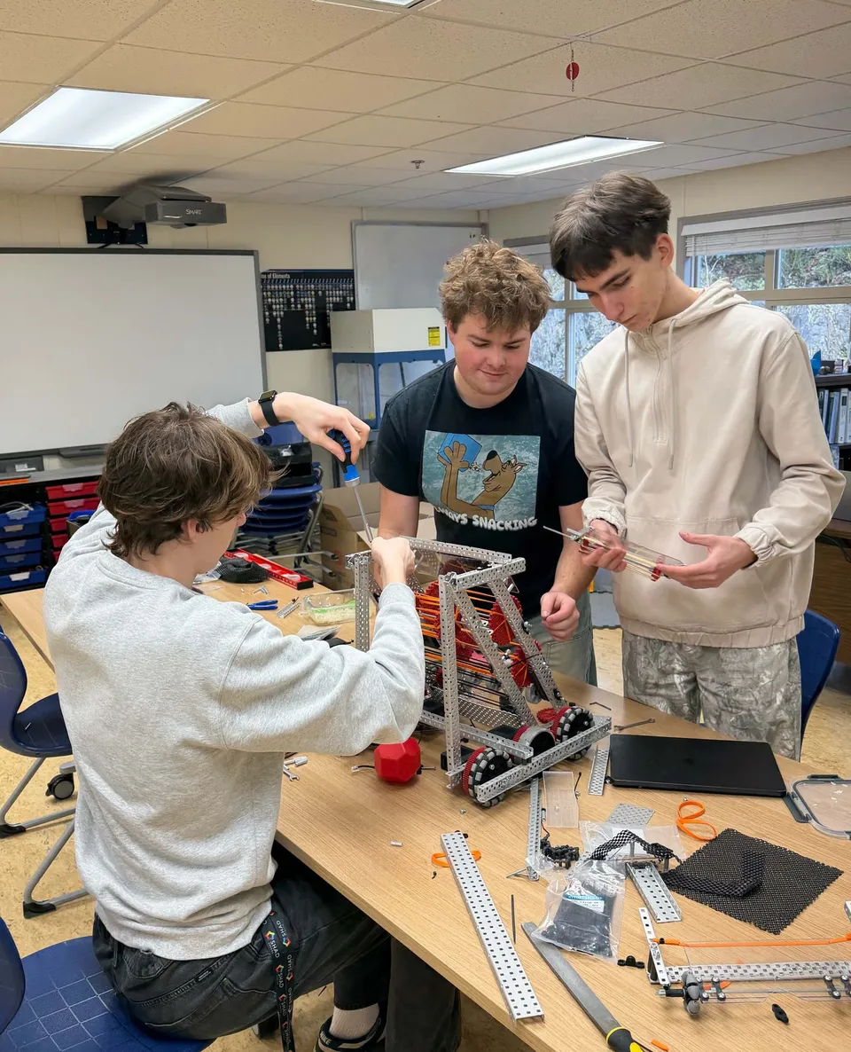 Tre studenti della Aspengrove School lavorano insieme alla costruzione di un robot in classe.