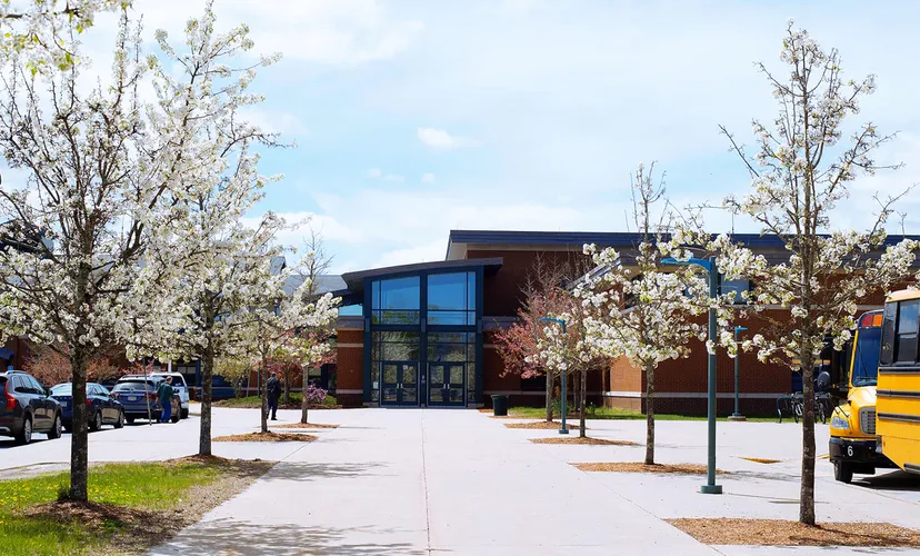 L'edificio moderno della Hopkinton High School con grandi finestre e alberi in fiore nell'area esterna.