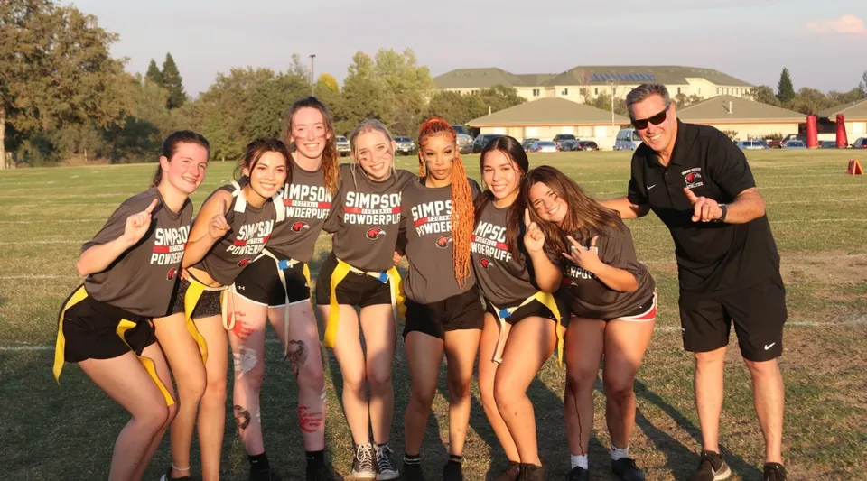 Un gruppo di giovani atlete posa insieme su un campo in erba nel campus della Simpson University.