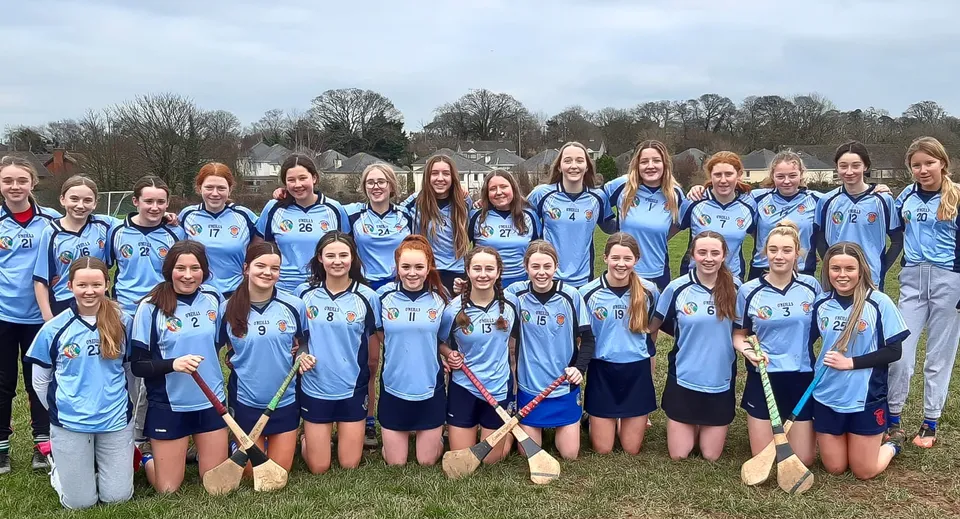 Un gruppo di giovani atlete in divisa azzurra si trova su un campo del St. Brigid's College.