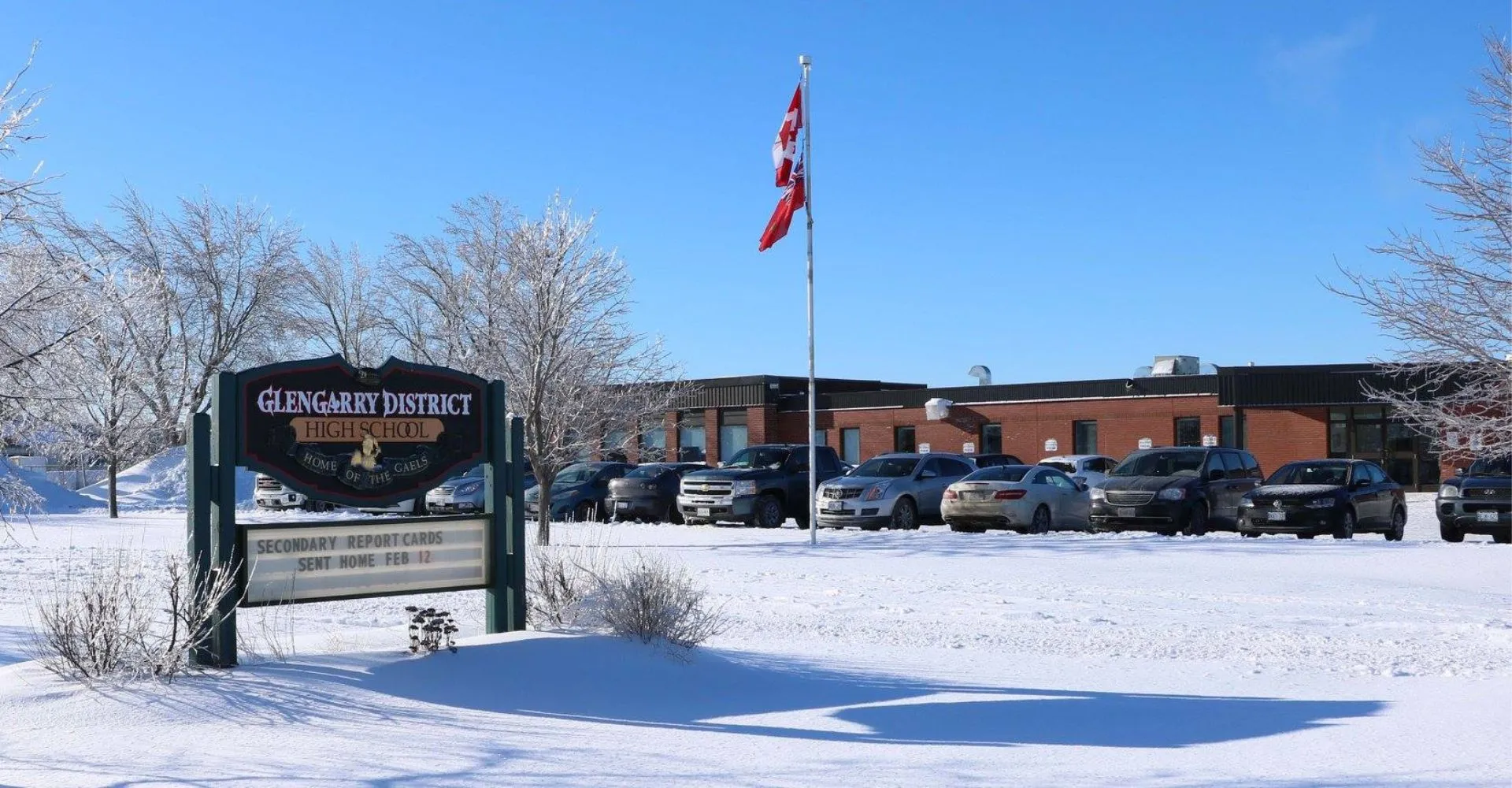 Uno scatto invernale con la neve, il cartello della Glengarry District High School e un edificio con la bandiera sullo sfondo.