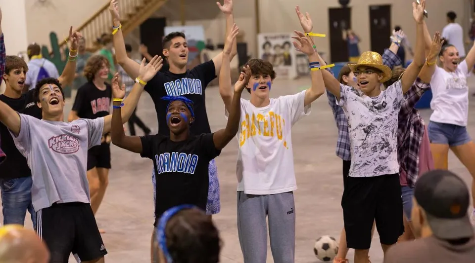 Un gruppo di studenti della Winston Salem Christian School esulta con le braccia alzate.