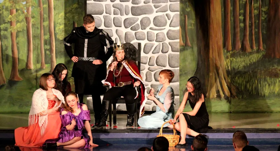 Studenti della Bishop Mahoney High School provano uno spettacolo teatrale davanti a un muro di pietra e a una scenografia con bosco.