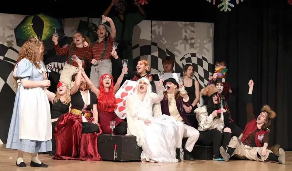 Studenti della Sir Wilfred Laurier Secondary School si esibiscono in costumi colorati su un palco con sfondo a scacchi.