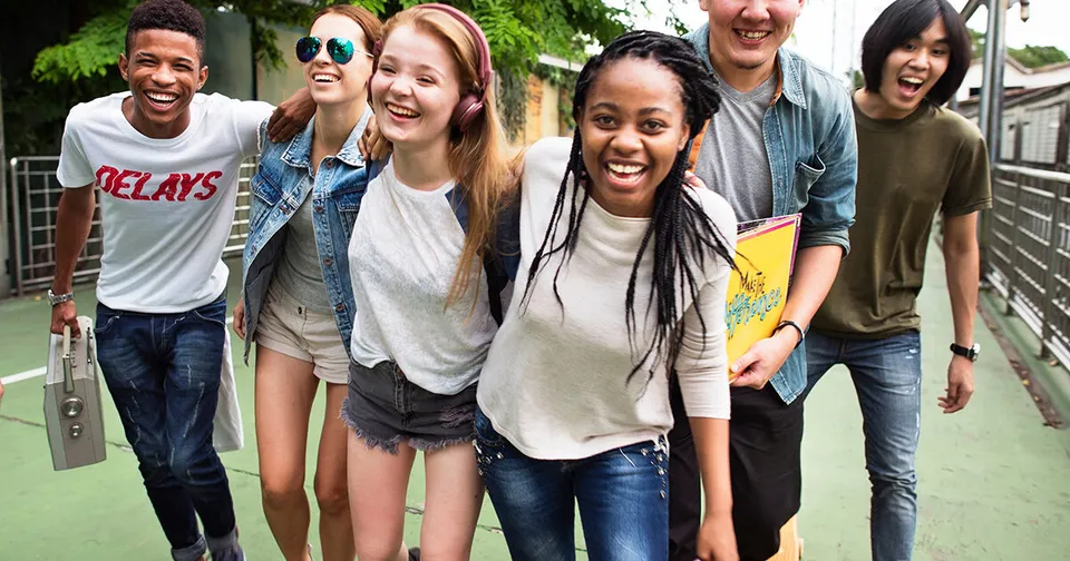 Un gruppo di studenti della École secondaire publique Carrefour Jeunesse all'aperto davanti a uno sfondo verde.