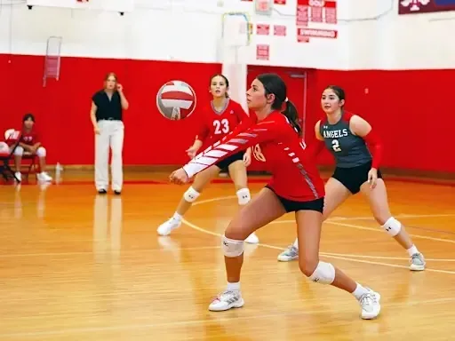 Jugadoras de voleibol de la Incarnate Word Academy se preparan en el gimnasio para la siguiente jugada.