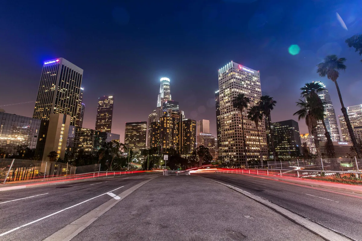 Skyline notturno di downtown Los Angeles con i grattacieli illuminati e le scie luminose delle auto