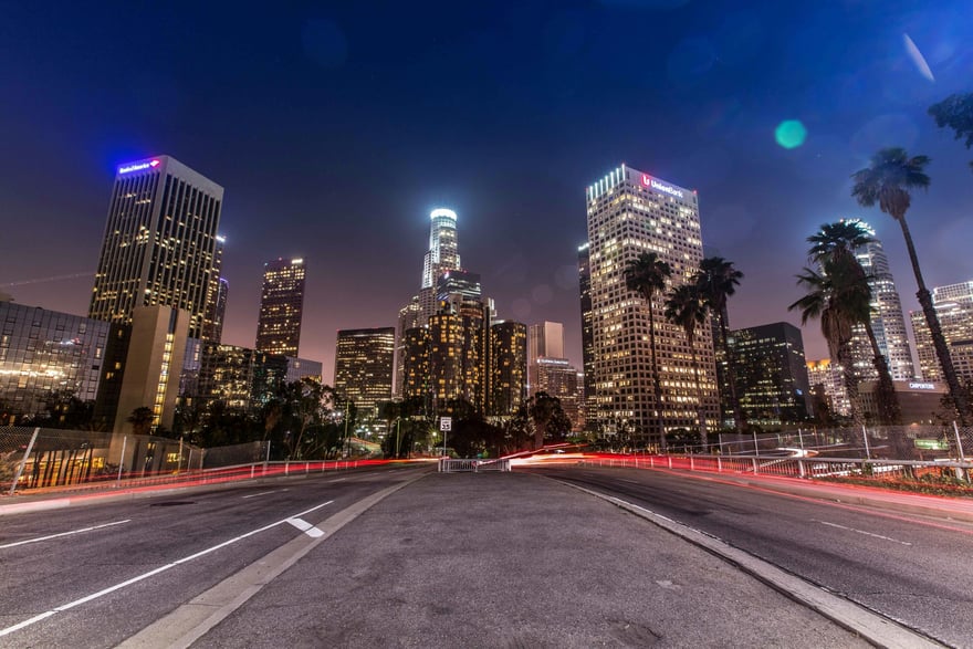 Skyline notturno di downtown Los Angeles con i grattacieli illuminati e le scie luminose delle auto