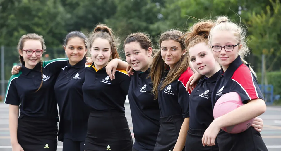 Un gruppo di studentesse della Archbishop's School sorride all'aperto davanti ad alberi e aree verdi.
