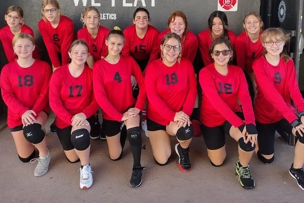 Un equipo deportivo femenino de la Parkhurst Academy posa con camisetas rojas para una foto de grupo.