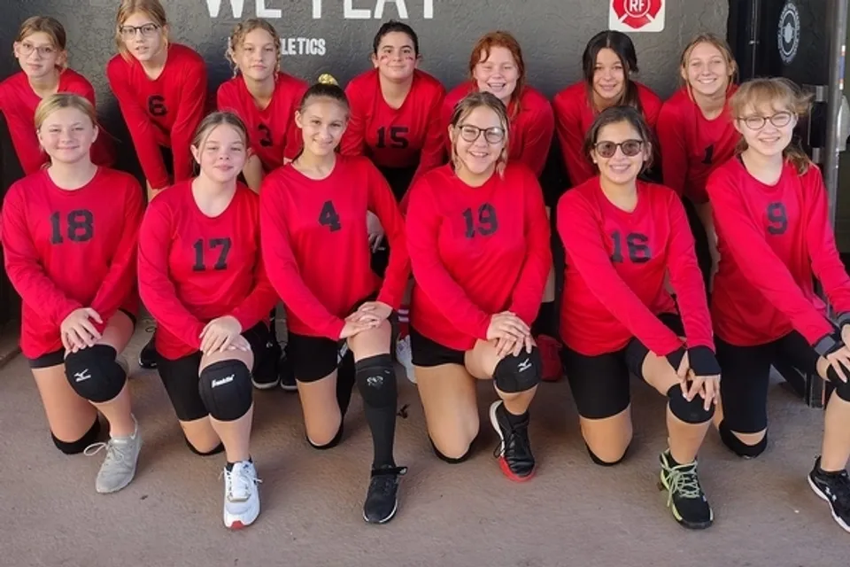 Una squadra sportiva femminile della Parkhurst Academy posa con maglie rosse per una foto di gruppo.