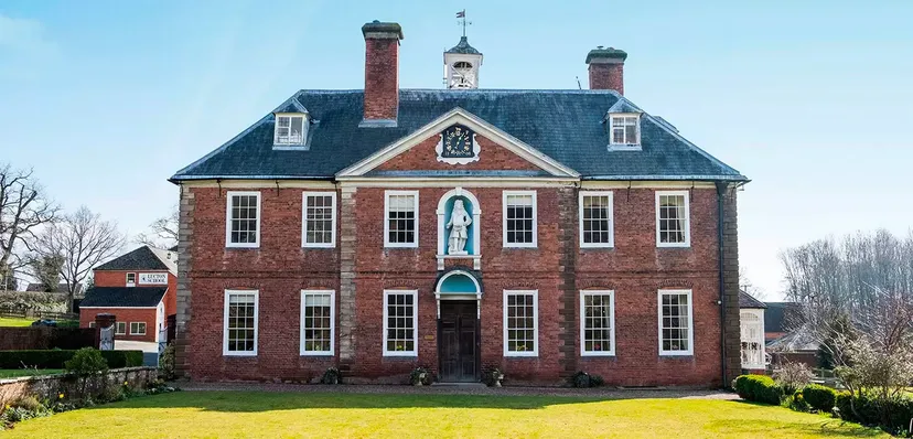 L'edificio storico della Lucton School sorge su un'area verde ben curata ed è circondato da alberi.