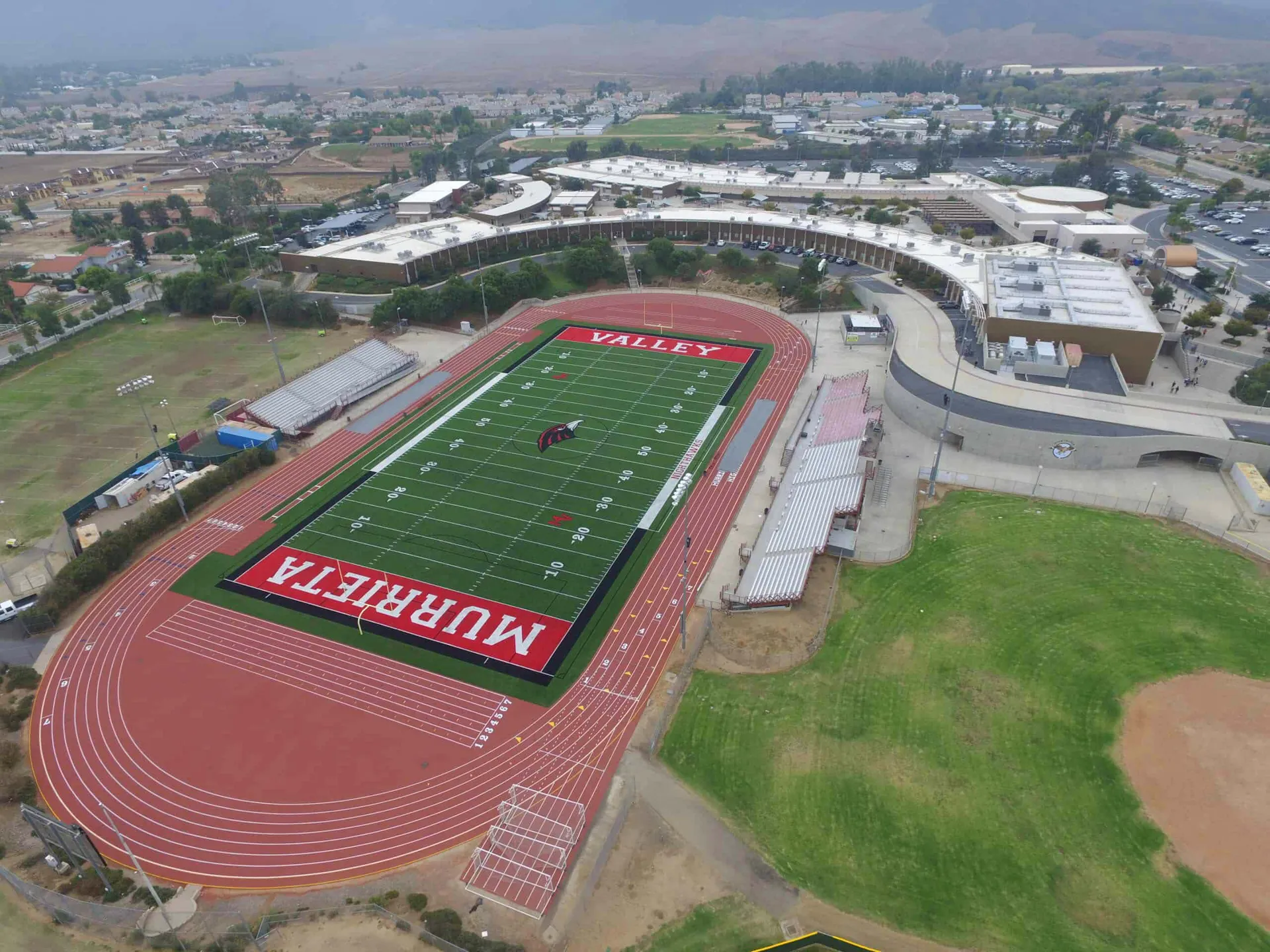 Vista aerea del grande stadio sportivo con campo da calcio rosso e pista di atletica nel Murrieta Valley Unified School District.