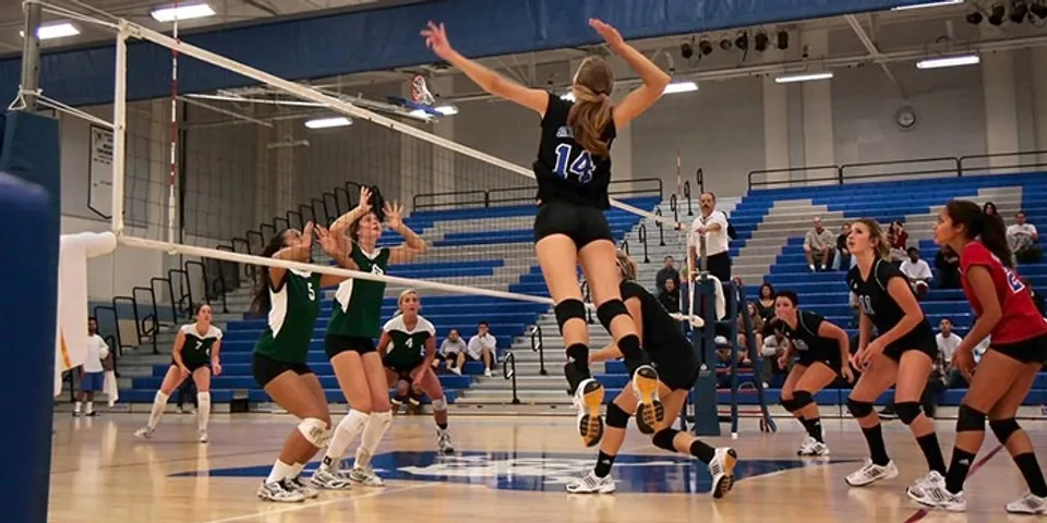 Giocatrici di pallavolo del Santa Monica College giocano un'intensa partita di pallavolo con una schiacciata sopra la rete.
