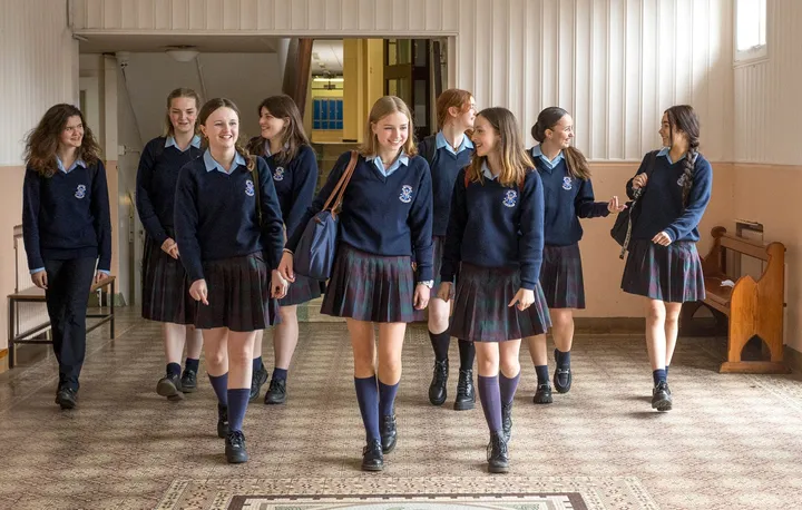 Estudiantes con uniforme caminando por un pasillo de la escuela