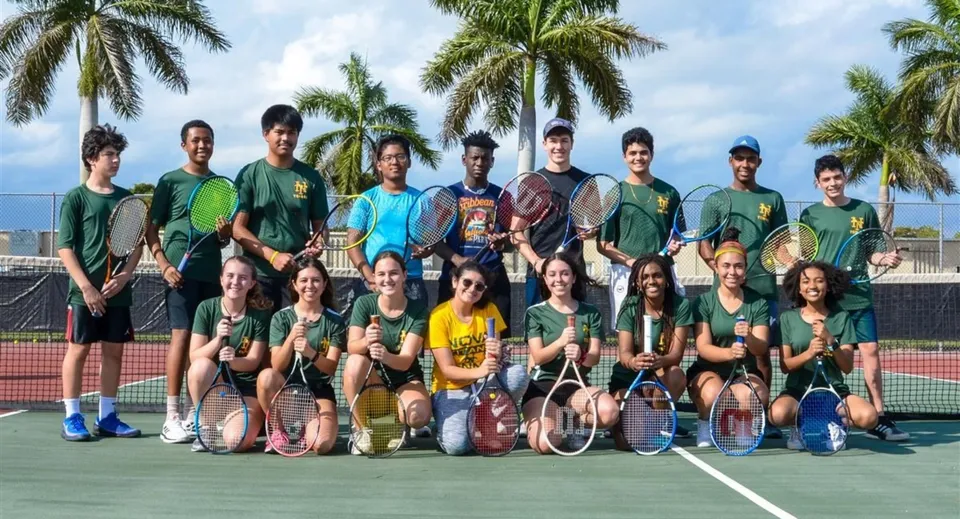 Un gruppo di studenti posa insieme sul campo da tennis della Central Christian School sotto un cielo blu e circondato da palme.
