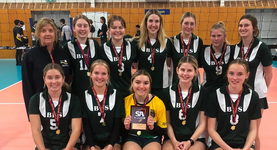 Un gruppo di giovani pallavoliste posa in divisa sul campo da pallavolo della Brighton Secondary School.
