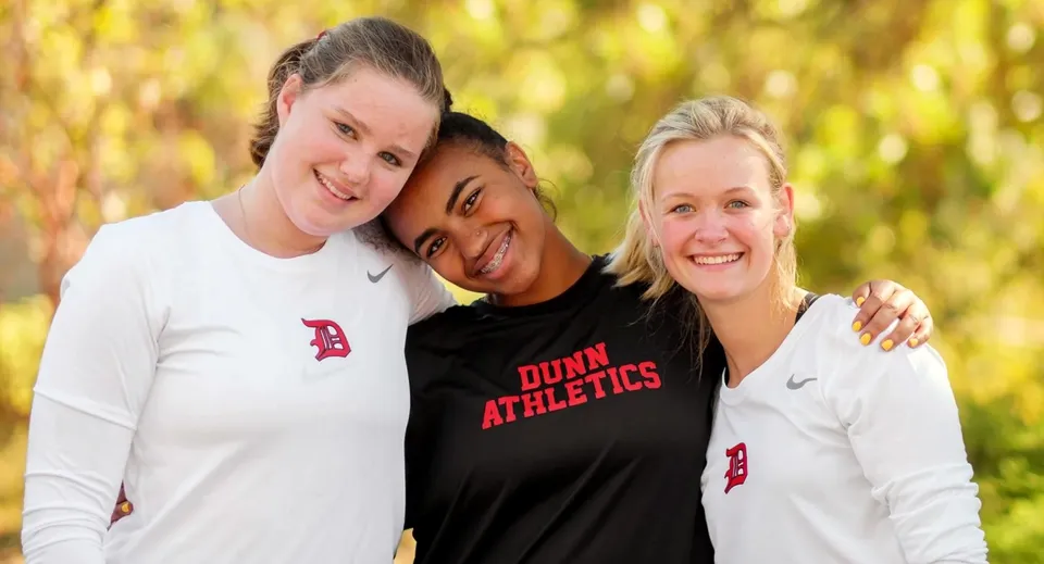 Tre studentesse della Dunn School posano all'aperto in abbigliamento sportivo davanti a uno sfondo naturale.