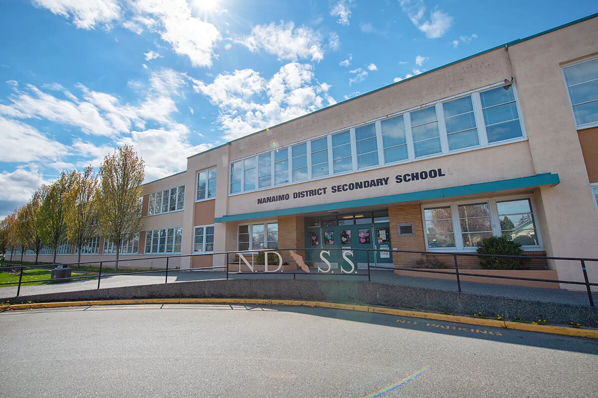 L'edificio scolastico moderno a più piani della Nanaimo District Secondary School con grandi finestre sotto un cielo blu.