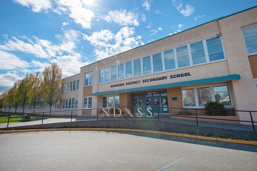L'edificio scolastico moderno a più piani della Nanaimo District Secondary School con grandi finestre sotto un cielo blu.