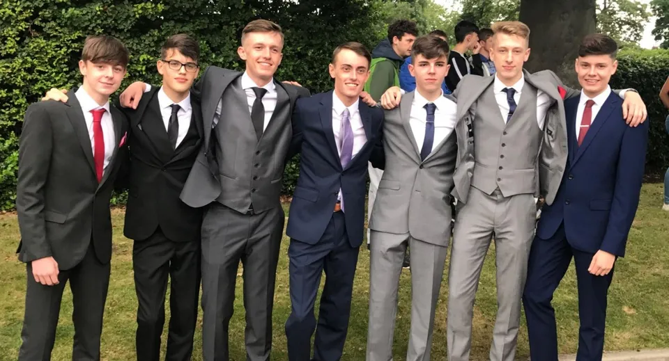 Un gruppo di studenti in abiti formali si trova nel verde nel campus del Christ's College.