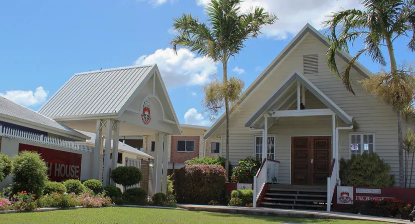 L'edificio in legno a due piani della Whitsunday Anglican School è circondato da verdi palme e piante.