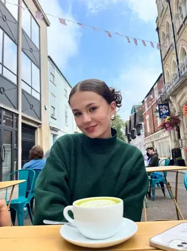 Chica con un té matcha en la terraza de una cafetería con banderines británicos