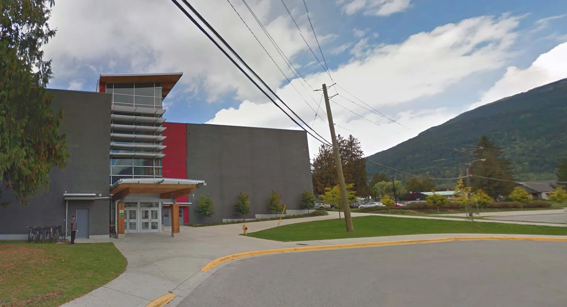 L'edificio moderno della Revelstoke Secondary School con facciata grigia e rossa davanti a uno sfondo montuoso.