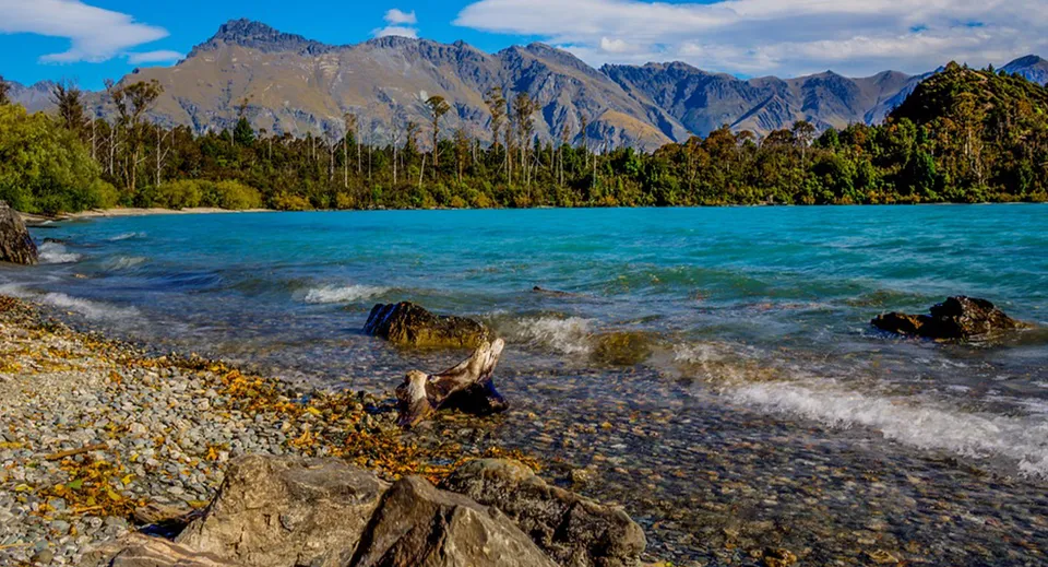 Un tranquillo lago alpino con montagne innevate e una riva rocciosa vicino a Kapiti College.