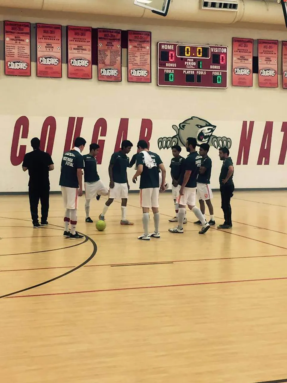 Un gruppo di studenti della Green Fields High School si trova insieme sul campo da basket davanti a un grande murale.